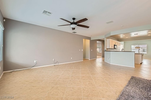 unfurnished living room featuring light tile patterned floors and ceiling fan