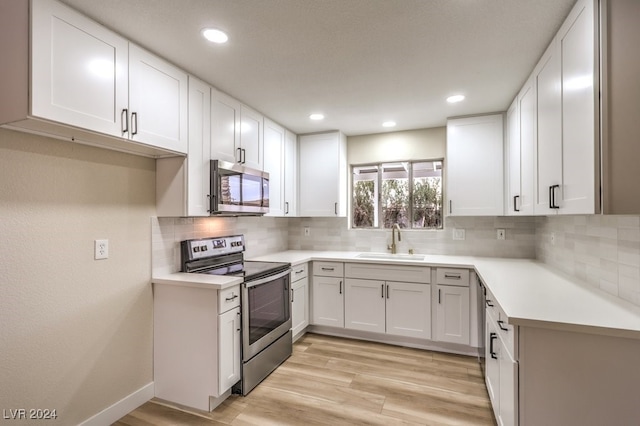 kitchen featuring decorative backsplash, appliances with stainless steel finishes, light wood-type flooring, sink, and white cabinets