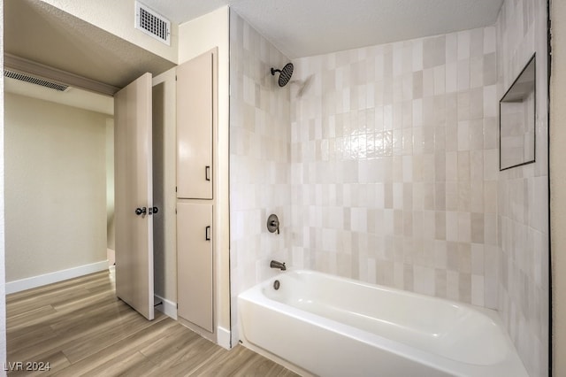 bathroom featuring a textured ceiling, wood-type flooring, and bathtub / shower combination