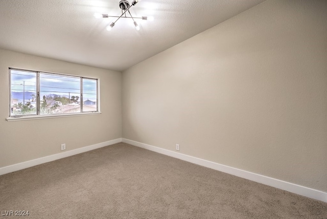 empty room with carpet floors, vaulted ceiling, and a notable chandelier