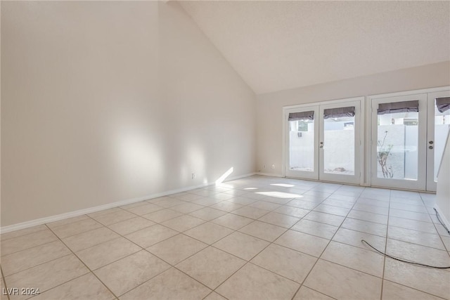 spare room with light tile patterned floors, high vaulted ceiling, and french doors