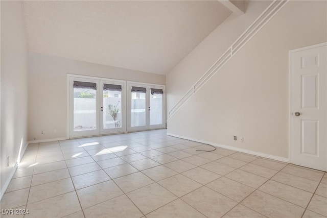 unfurnished room with french doors, lofted ceiling with beams, and light tile patterned floors