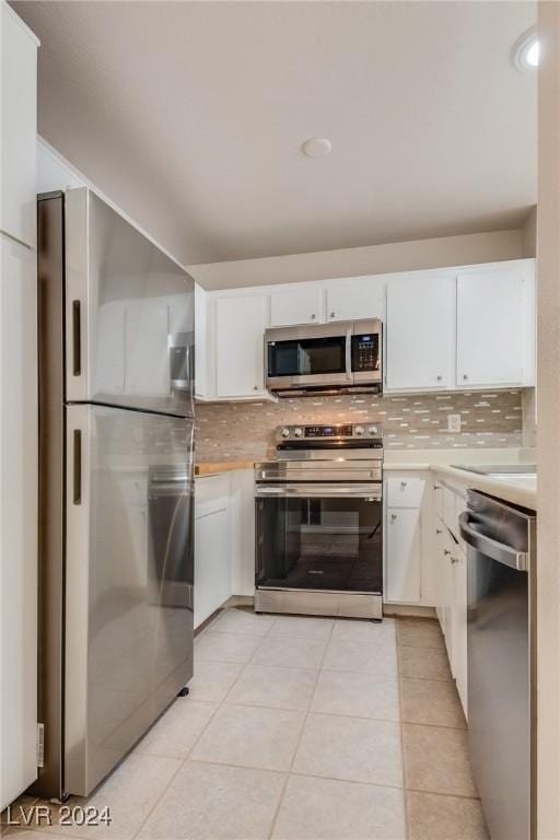 kitchen featuring white cabinets, decorative backsplash, light tile patterned floors, and appliances with stainless steel finishes