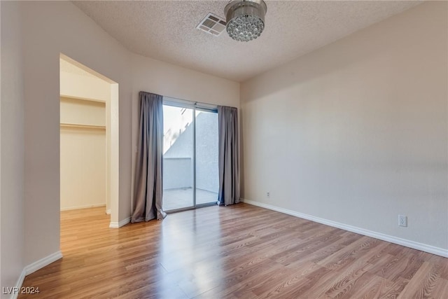 unfurnished room with light hardwood / wood-style floors and a textured ceiling