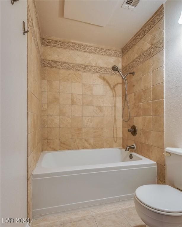 bathroom featuring tile patterned flooring, toilet, and tiled shower / bath