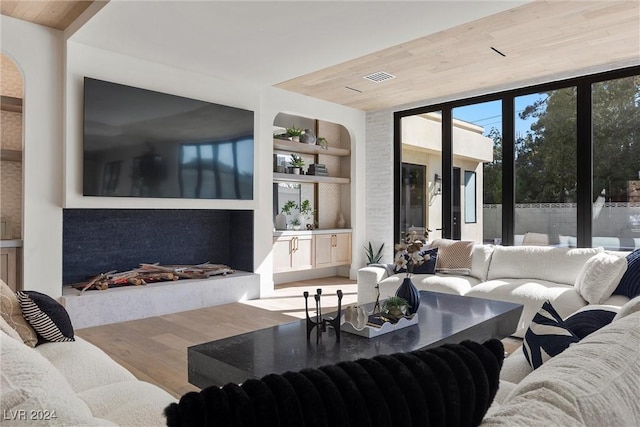 living room with built in shelves, visible vents, expansive windows, wood finished floors, and wooden ceiling