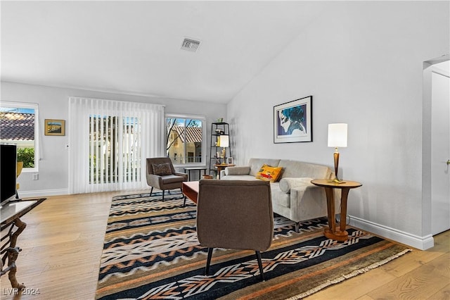 living room with vaulted ceiling, light hardwood / wood-style flooring, and a wealth of natural light