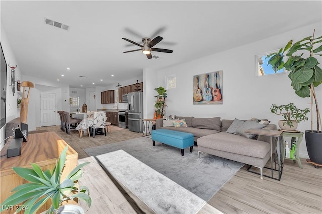 living room with light wood-type flooring, ceiling fan, and sink