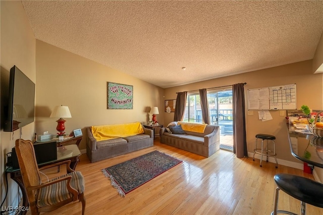 living room featuring light wood-type flooring, a textured ceiling, and lofted ceiling