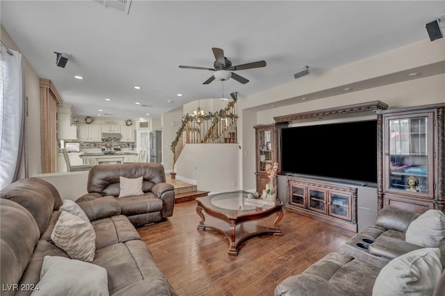 living room with ceiling fan with notable chandelier and light wood-type flooring