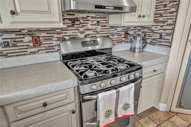 kitchen featuring gas stove, decorative backsplash, range hood, and light stone counters