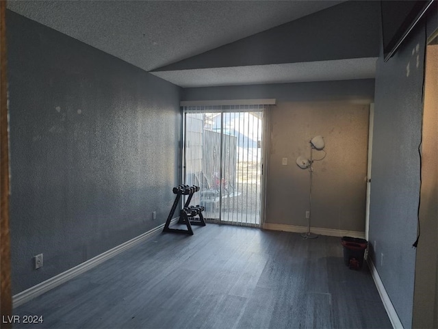 spare room with dark hardwood / wood-style flooring, a textured ceiling, and vaulted ceiling