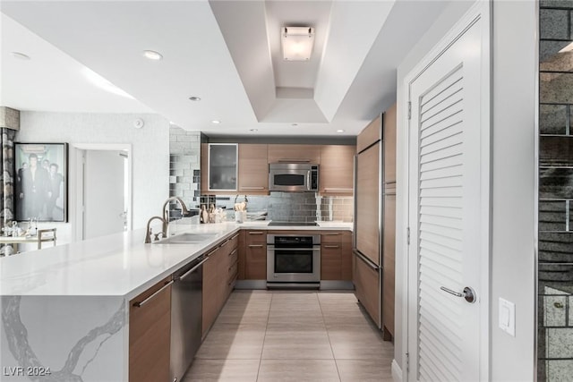 kitchen featuring kitchen peninsula, backsplash, stainless steel appliances, and light tile patterned flooring