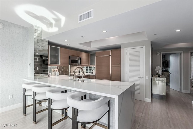 kitchen with a breakfast bar, kitchen peninsula, tasteful backsplash, and paneled built in refrigerator