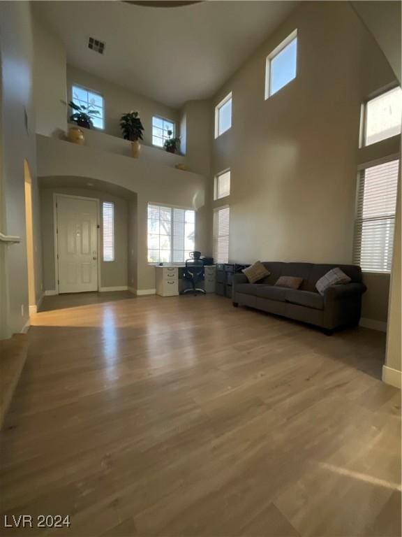 unfurnished living room featuring wood-type flooring and a towering ceiling