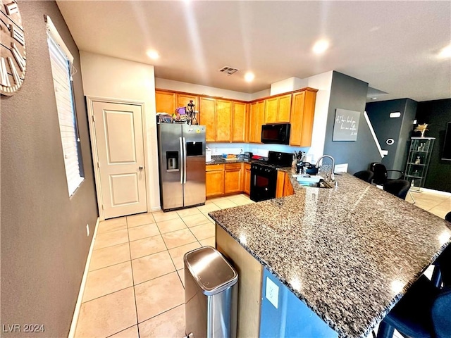 kitchen with black appliances, a kitchen bar, sink, kitchen peninsula, and light tile patterned floors