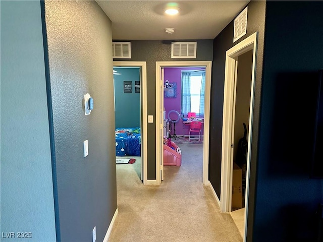 corridor with a textured ceiling and light carpet