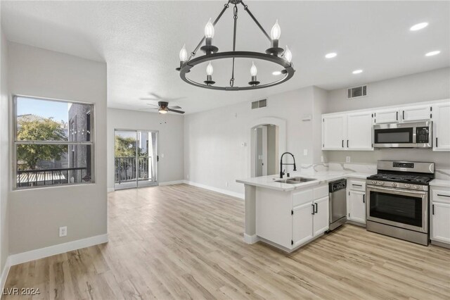 kitchen featuring kitchen peninsula, appliances with stainless steel finishes, ceiling fan with notable chandelier, sink, and white cabinetry