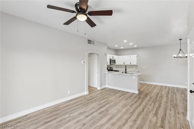 unfurnished living room with light wood-style flooring, recessed lighting, ceiling fan with notable chandelier, visible vents, and baseboards