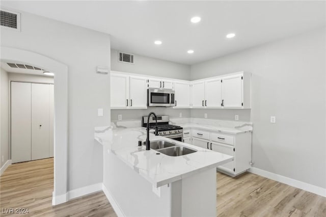 kitchen with visible vents, appliances with stainless steel finishes, white cabinets, light stone countertops, and a peninsula