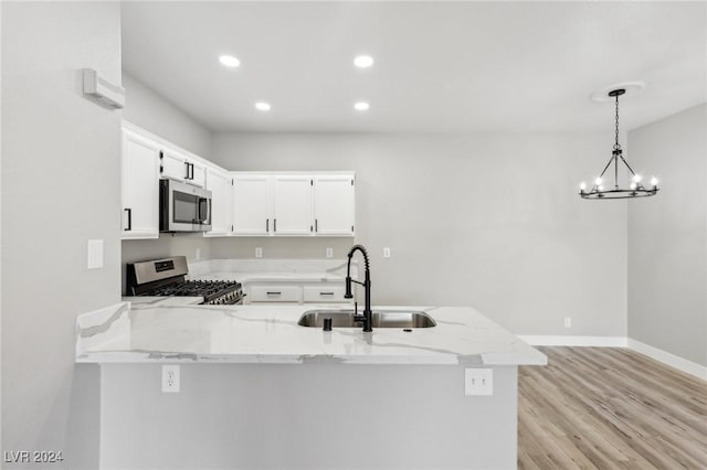 kitchen featuring light stone counters, a peninsula, a sink, white cabinets, and appliances with stainless steel finishes