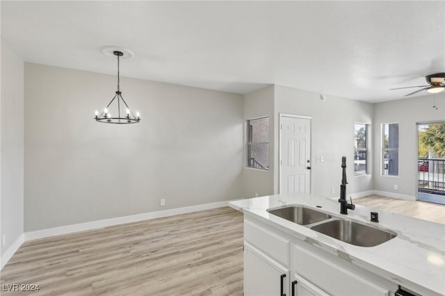 kitchen with light wood-style flooring, open floor plan, a sink, and decorative light fixtures