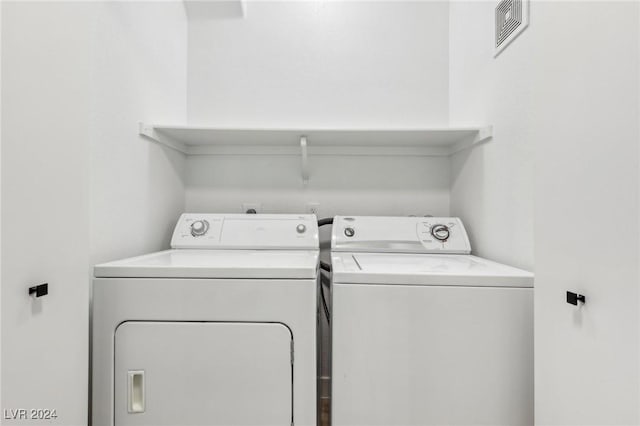 washroom with laundry area, visible vents, and washer and clothes dryer