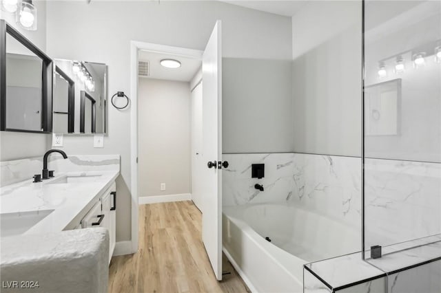 bathroom featuring double vanity, visible vents, a sink, wood finished floors, and a bath