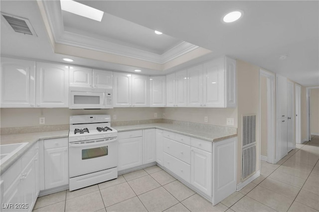 kitchen featuring white appliances, ornamental molding, a tray ceiling, and white cabinets