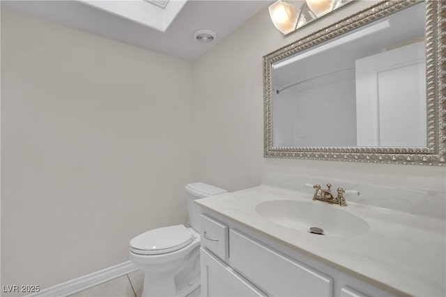 bathroom with vanity, toilet, a skylight, and tile patterned flooring