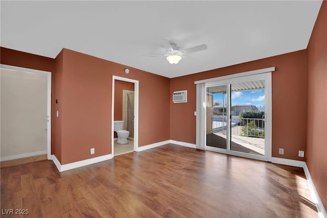 empty room featuring wood-type flooring, a wall unit AC, and ceiling fan