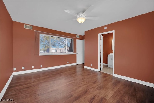 unfurnished bedroom featuring ceiling fan, ensuite bathroom, and dark hardwood / wood-style floors