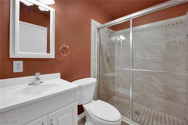 bathroom featuring a shower with door, vanity, and toilet