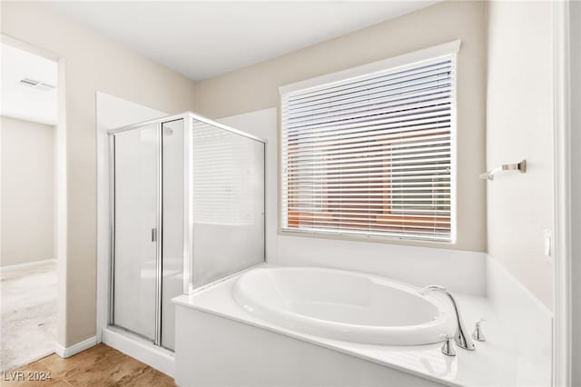 bathroom with shower with separate bathtub and a wealth of natural light