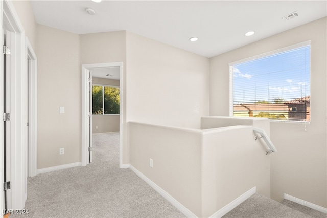 hall with light colored carpet and a wealth of natural light