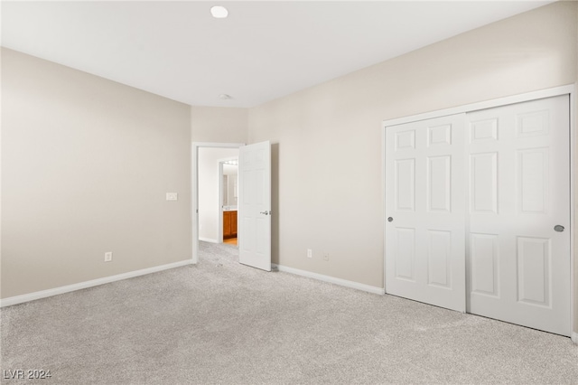 unfurnished bedroom with light colored carpet and a closet