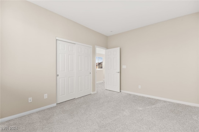 unfurnished bedroom with light colored carpet and a closet