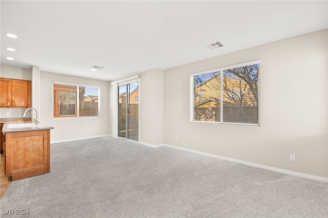 unfurnished living room with light carpet and sink