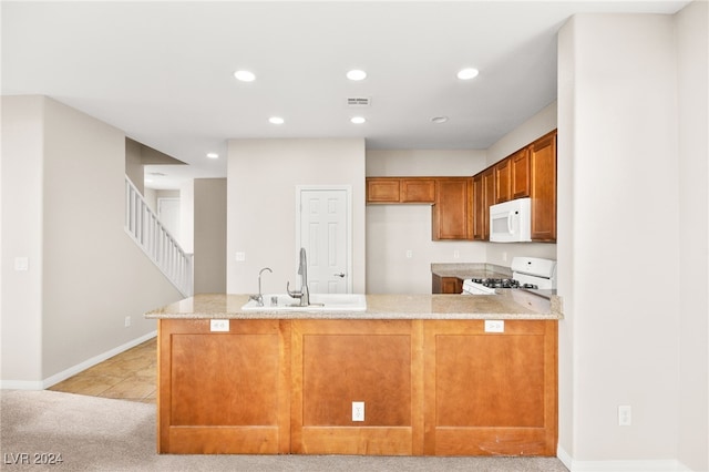 kitchen featuring white appliances, sink, light stone countertops, light colored carpet, and kitchen peninsula