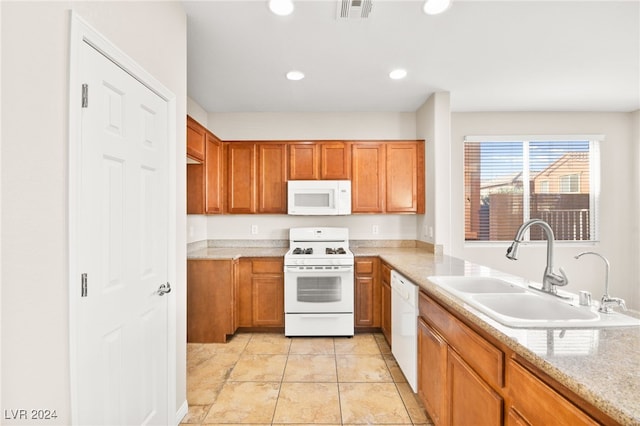 kitchen featuring light stone countertops, sink, light tile patterned floors, and white appliances