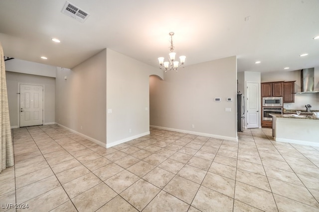 tiled empty room featuring an inviting chandelier