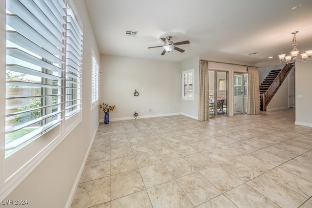 empty room featuring light tile patterned floors and ceiling fan with notable chandelier