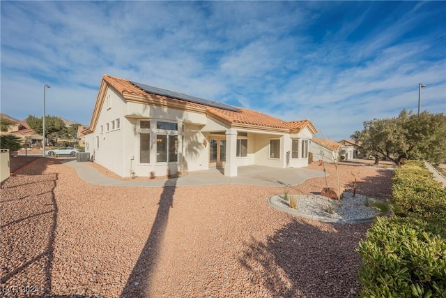 back of property featuring a patio area, french doors, cooling unit, and solar panels