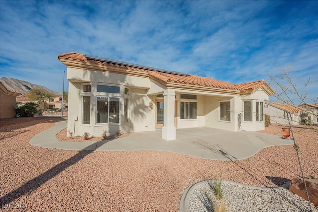 rear view of house with a patio and solar panels