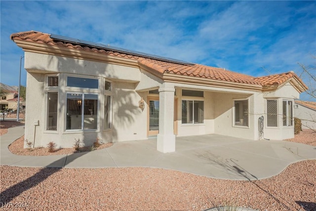 rear view of property featuring solar panels and a patio area