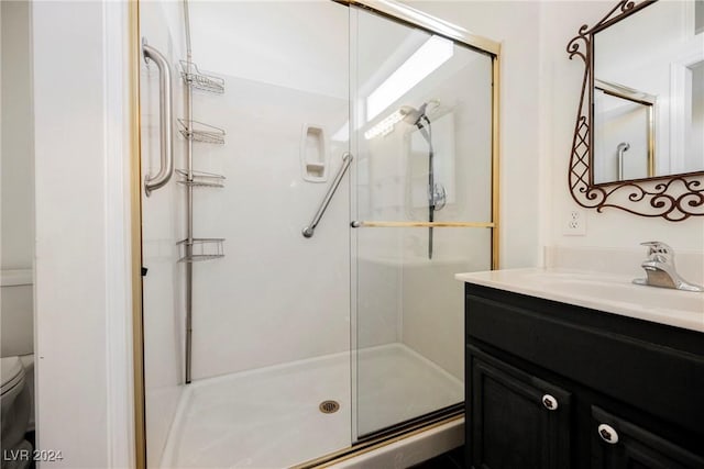 bathroom with vanity, toilet, and a shower with shower door