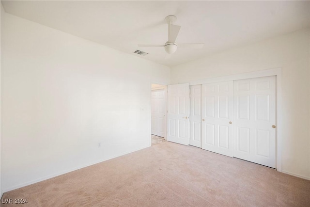 unfurnished bedroom with light carpet, a closet, and ceiling fan