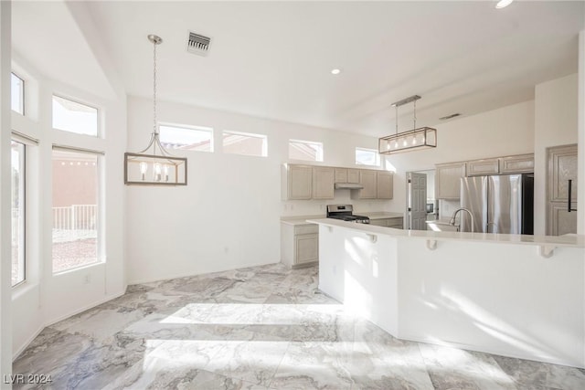 kitchen featuring light brown cabinets, stainless steel appliances, a wealth of natural light, and hanging light fixtures