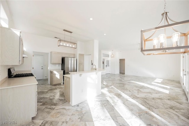 kitchen featuring stainless steel refrigerator, an island with sink, pendant lighting, and range