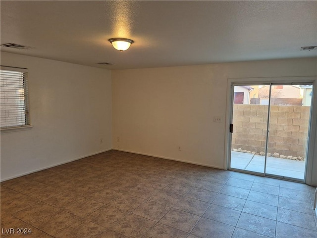 empty room with a textured ceiling and light tile patterned floors